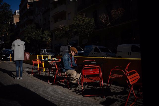 Archivo - Un hombre sentado en una terraza en Barcelona, en una foto de archivo. 