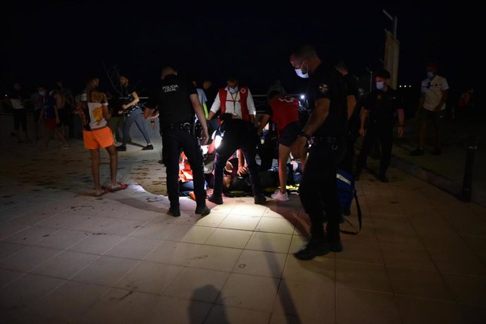 Agentes y empleados de Cruz Roja ayudan a grupos de migrantes tras su llegada a la playa del Tarajal.