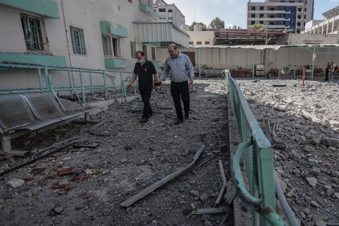 18 May 2021, Palestinian Territories, Gaza City: Palestinians inspect the damage to the Palestinian Ministry of Health building and Al-Rimal dispensary, as a result of an Israeli airstrike on a target next to the ministry, amid the escalating flare-up o