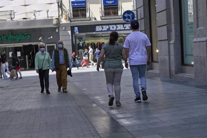 Varias personas pasean por las inmediaciones de la Puerta del Sol con mascarilla.