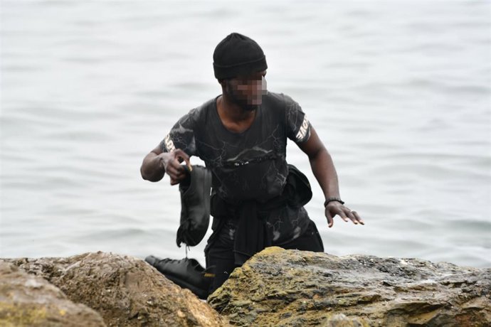 Un migrante llega con sus zapatillas a la orilla en una jornada marcada por las devoluciones en caliente que están efectuando a los migrantes que han entrado en Ceuta procedente de Marruecos, a 18 de mayo de 2021, en Ceuta, (España). 