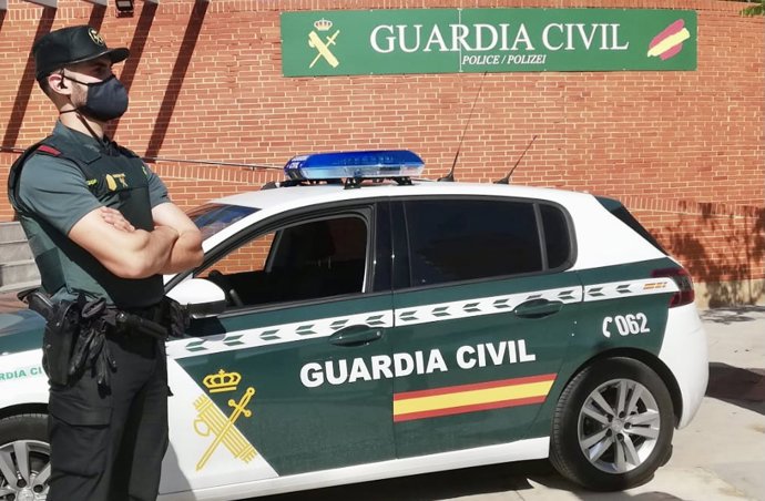 Archivo - Un agente de la Guardia Civil, junto a un vehículo del cuerpo.