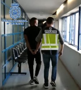 El detenido por propinar golpes a otro hombre en una pelea y arrojarlo al agua de una patada, escoltado por un policía nacional