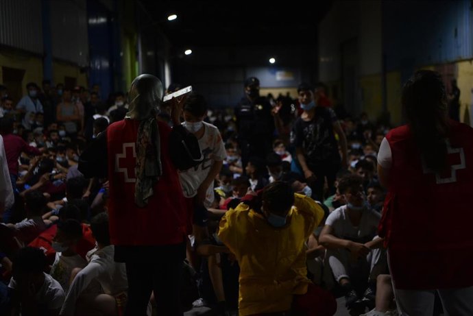 Empleados de Cruz Roja ayudan a grupos de migrantes tras su llegada a la playa del Tarajal, a 17 de mayo de 2021, en Ceuta (España). España ha movilizado al Ejército en la ciudad tras la entrada de más de 5.000 marroquíes en 24 horas.