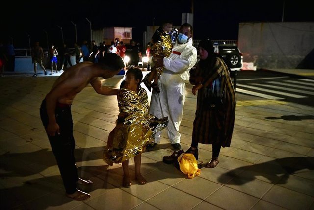 Un hombre migrante coge en brazos a un menor acompañado de una mujer y una niña pequeña, a 17 de mayo de 2021, en Ceuta (España). España ha movilizado al Ejército en la ciudad tras la entrada de más de 5.000 marroquíes en 24 horas.