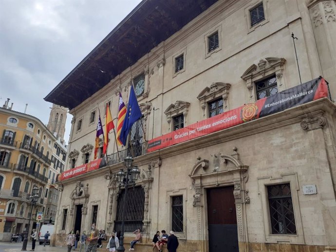 La fachada del Ayuntamiento de Palma luce la bandera de apoyo al Real Club Mallorca.