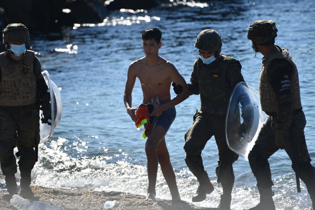 Un militar del ejército español ayuda a un menor migrante procedente de Marruecos a su llegada a Ceuta, a 19 de mayo