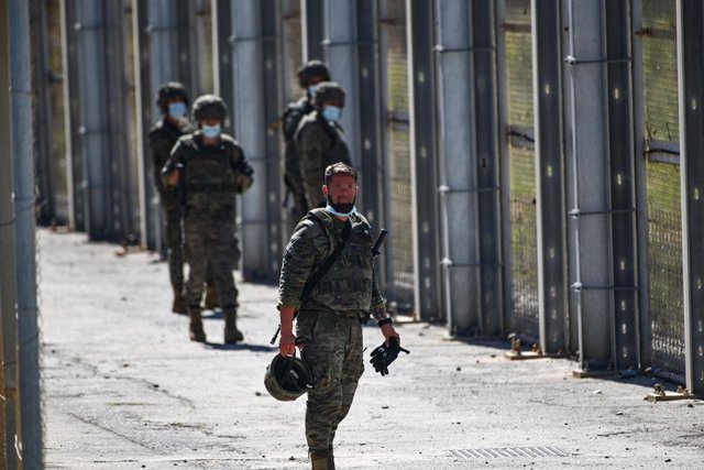 Varios militares vigilan desde la valla que separa Ceuta de Marruecos la llegada de migrantes