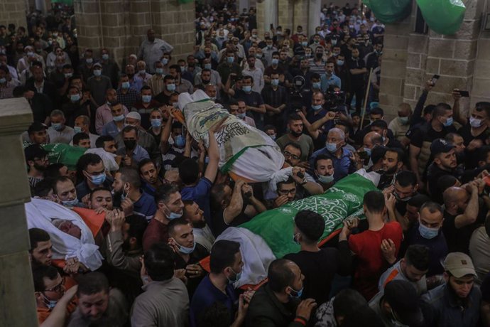 13 May 2021, Palestinian Territories, Gaza City: Mourners carry the bodies of 13 fighters of the Islamist Hamas movement, who were killed in Israeli airstrikes, during their funeral at Al-Omari Mosque in Gaza City. The Ministry of Health in Gaza Strip s