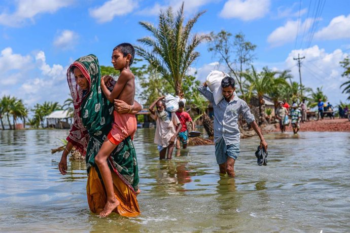 Archivo - Un grupo de personas cruza una carretera inundada en Bangladesh tras el paso del ciclón 'Amphan'