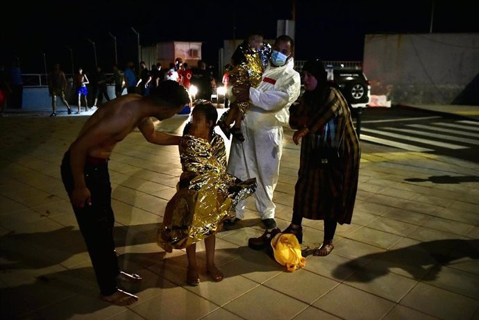 Un hombre migrante coge en brazos a un menor acompañado de una mujer y una niña pequeña, a 17 de mayo de 2021, en Ceuta (España). 