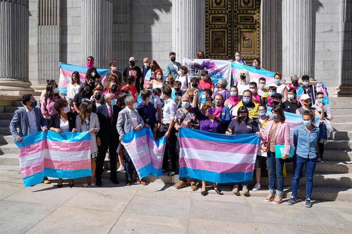 Varias personas y demás autoridades posan con banderas trans en las escaleras del Congreso