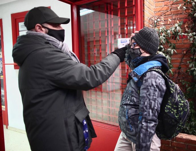 Archivo - Un trabajador toma la temperatura a un alumno antes de entrar a un colegio. 