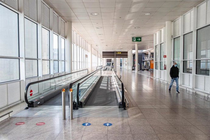 Archivo - Un pasajero con mascarilla pasea por las instalaciones del aeropuerto El Prat de Barcelona, en una imagen de archivo