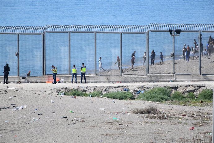 Agentes vigilan desde la valla que separa Ceuta de Marruecos la llegada de migrantes, a 19 de mayo de 2021, en Ceuta, (España). Los intentos de llegar a Ceuta no han cesado desde el lunes y pasadas 72 horas el balance de migrantes que han llegado a terr