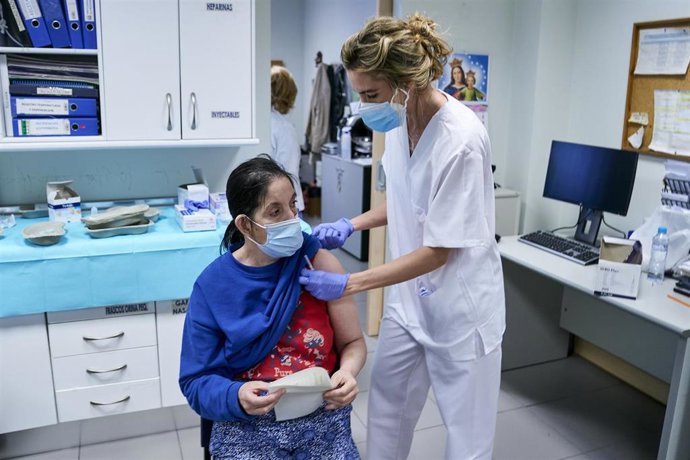 Una sanitaria vacuna a una mujer sin hogar en el Centro de Acogida Municipal Para Personas Sin Hogar San Isidro, a 20 de mayo de 2021, en Madrid (España). La visita coincide con el inicio de la vacunación para personas sin hogar en los centros municipal