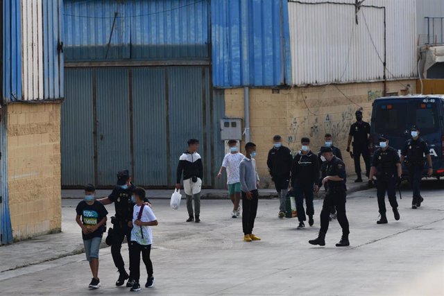 Agentes de la Policía Nacional acompañan a menores marroquíes a las naves acondicionadas anexas a la frontera del Tarajal en Ceuta a 20 de mayo de 2021 