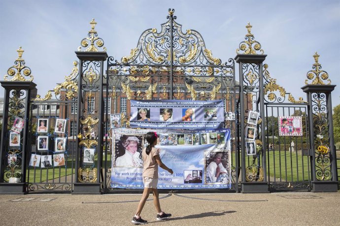Archivo - 30 August 2019, England, London: A young girl walks past the gates of Kensington Palace, where people have attached posters and pictures of Princess Diana, as the anniversary of her death is expected to be marked by family, friends and fans on