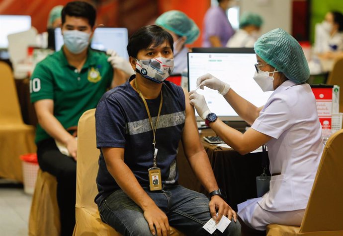 Una trabajadora sanitaria vacuna a un hombre en Tailandia.