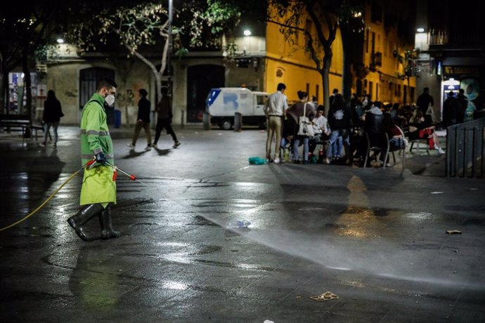 Un home rega un carrer de Barcelona, una setmana després de la fi de l'estat d'alarma, a Barcelona