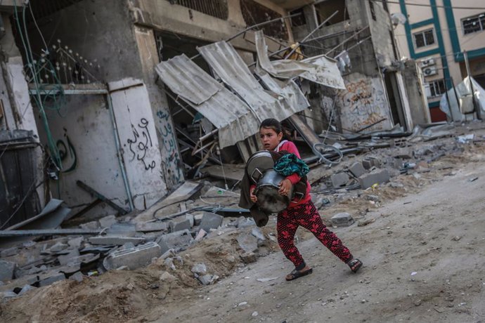 FILED - 20 May 2021, Palestinian Territories, Jabalia: A Palestinian girl carries her belongings at the site of a destroyed residential building after it was hit during Israeli airstrikes, amid the escalating flare-up of Israeli-Palestinian violence. Ph