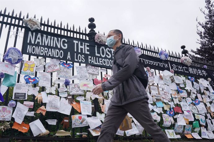 Archivo - Un hombre con mascarilla junto a un memorial en recuerdo a los fallecidos por coronavirus en EEUU