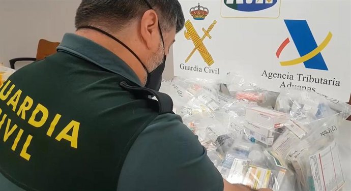 Un agente de la Guardia Civil junto a los medicamentos interceptados en el aeropuerto de Palma.