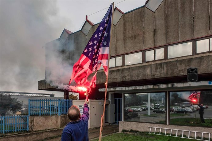 Archivo - Un trabajador de Alcoa San Cibrao quema una bandera de Estados Unidos delante de la factoría tras conocer la anulación del TSXG del ERE de la empresa en Cervo.