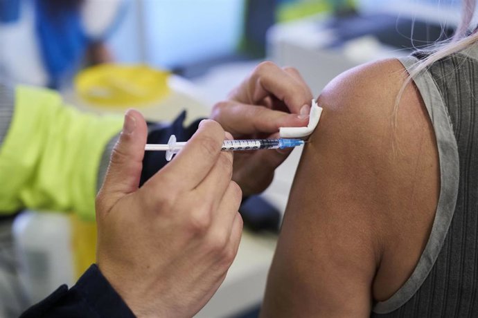 Un sanitario vacuna a una mujer 