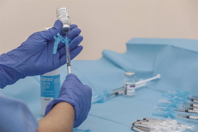 Archivo - Una profesional sanitaria sostiene una jeringuilla junto a un vial con la vacuna de AstraZeneca