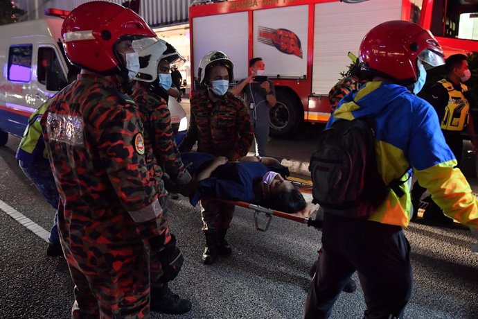Los trabajadores de emergencia transportan a un pasajero lesionado después de que dos trenes de Light Rail Transit (LRT) chocaran cerca de la estación de Kampung Baru.