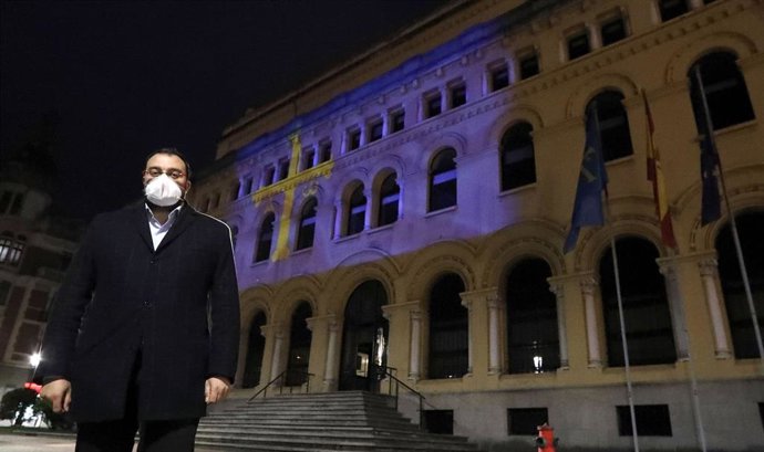 El presidente del Principado de Asturias, Adrián Barbón, ante la sede de la Presidencia del Gobierno del Principado, sobre la que esta noche se proyecta la imagen de la bandera de Asturias con motivo de la conmemoración del 25 de mayo de 1808.
