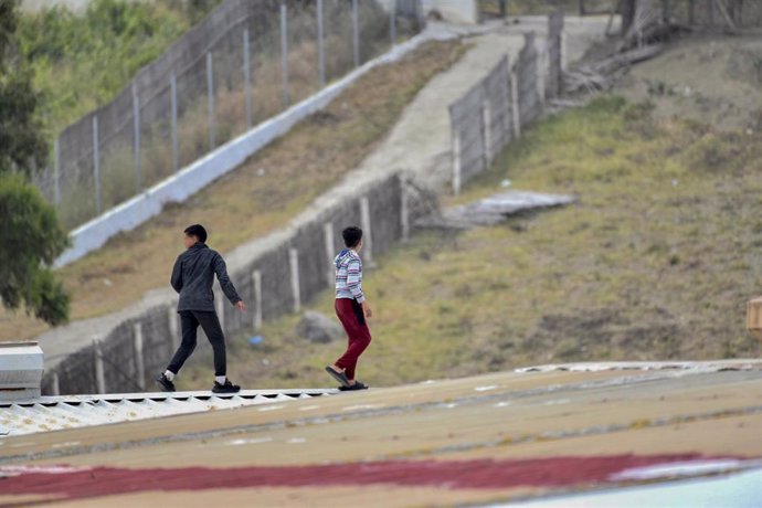 Varios niños caminan por un tejado al tratar de escapar de la nave de primera acogida del polígono del Tarajal, en Ceuta, en una imagen del 20 de mayo