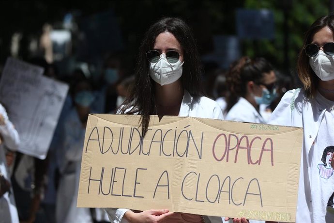 Una mujer sujeta un cartel en el que se lee: "Adjudicación opaca huele a cloaca", en la manifestación convocada por la plataforma FSE Unida como protesta al sistema de adjudicación de plazas para el MIR este año frente al Ministerio de Sanidad, a 25 de 