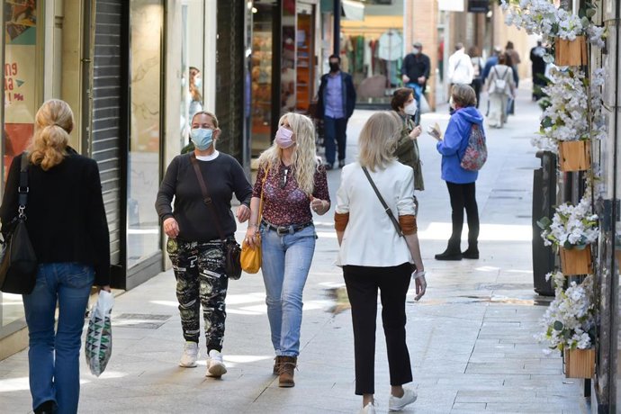 Ciudadanos pasean por una calle con mascarillas