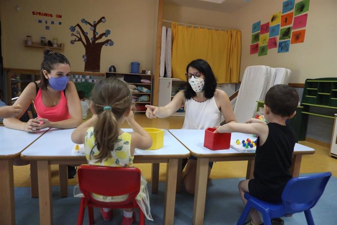 Archivo - Dos docentes imparten clases a varios alumnos en la Escuela Infantil El Tren de la Fresa, en Madrid