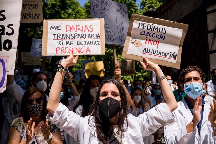 25 May 2021, Spain, Madrid: A protester holds placards during the Resident Internal Doctors (MIR) demonstration in front of the Spanish Ministry of Health, to show their rejection of the new requirements for the choice of specialized health training pla