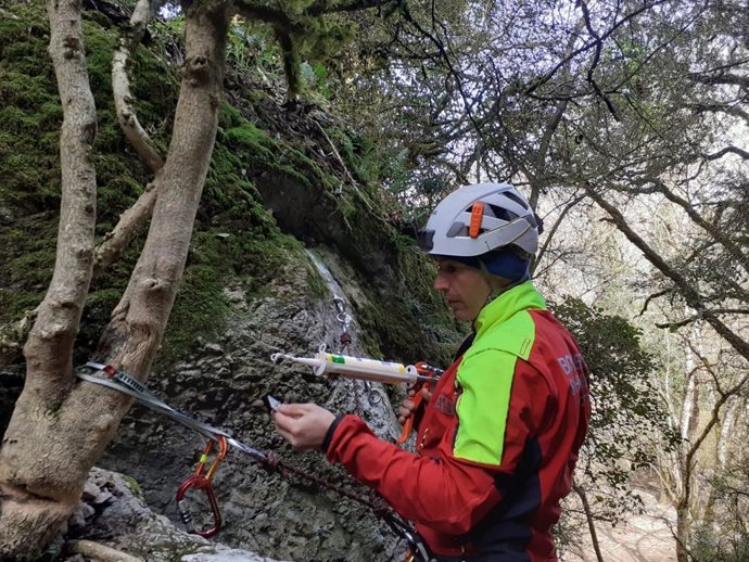 Un bombero del Grupo de Rescate Técnico coloca la placa en una de las paredes del barranco