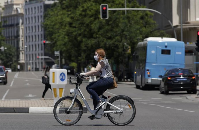 Archivo - Una mujer protegida con mascarilla monta en una bicicleta de BiciMAD 