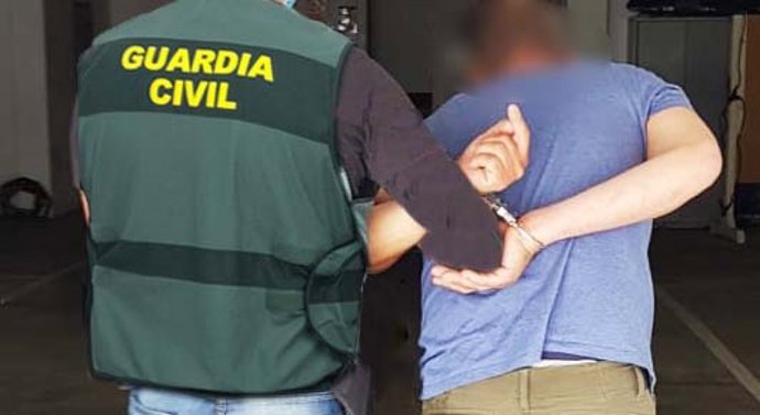 Un agente de la Guardia Civil traslada a un detenido.