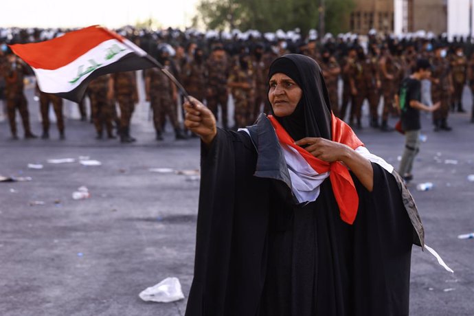 25 May 2021, Iraq, Baghdad: A woman with Iraqi flag takes part in an anti-government protest calling for the killers of pro-reform activists to be revealed. Photo: Ameer Al Mohammedaw/dpa