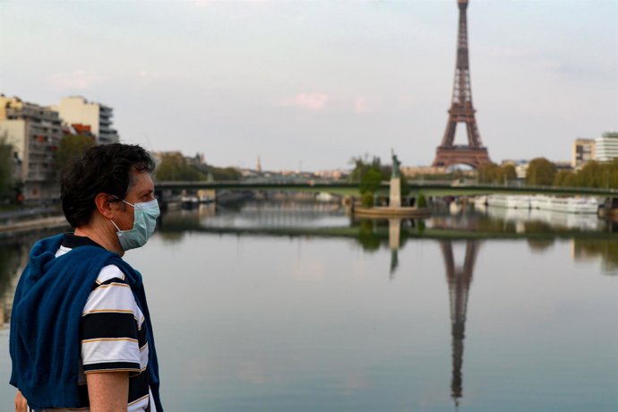 Archivo - Un hombre con mascarilla con la Torre Eiffel de fondo