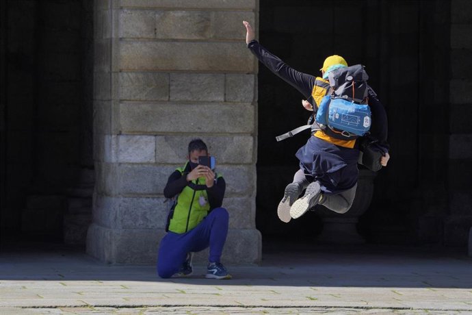 Archivo - Un peregrino se fotografía saltando en la Catedral de Santiago durante el puente de San José, en Santiago de Compostela