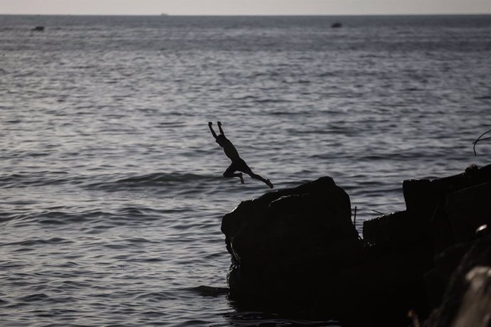 27 May 2021, Palestinian Territories, Gaza City: A Palestinian jumps on the water of the Mediterranean, as life begins to return to normalcy, after a ceasefire was reached last week after 11 days of deadly confrontations between Israel and the Palestini
