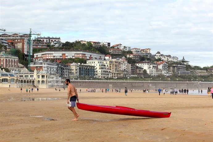 Archivo - Un hombre arrastra una canoa en la playa de La Concha en el día en que el Gobierno permite salir a hacer deporte de forma individual y pasear con otra persona con la que se conviva, a determinadas horas, según la edad, y hasta un kilómetro de 