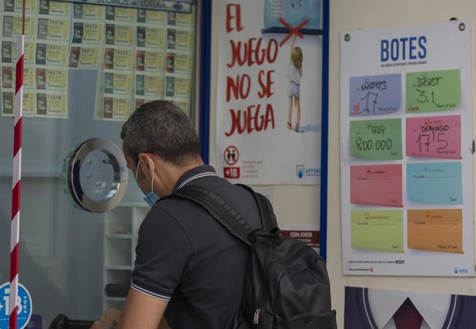 Archivo - Una persona compra lotería en una administración 