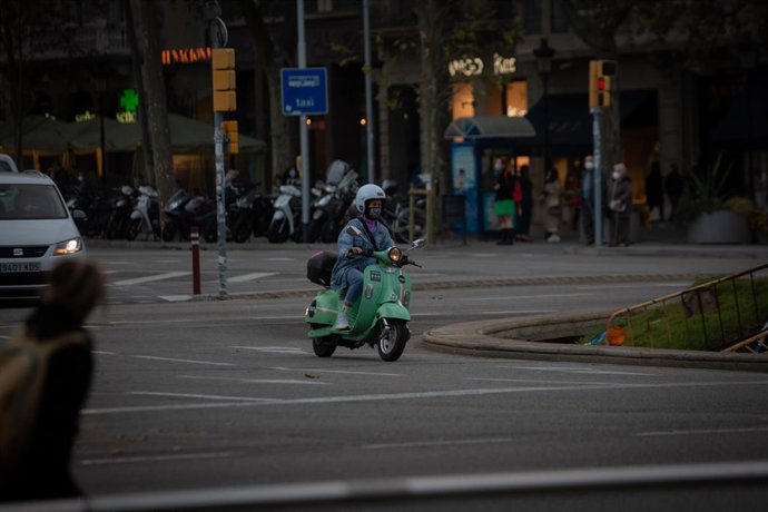 Archivo - Una mujer subida en una motocicleta, en Barcelona, Catalunya (España), a 25 de noviembre de 2020.   La propuesta de Plan de Movilidad Urbana (PMU) de Barcelona plantea que en 2024 un 81,52% de los desplazamientos se hagan a pie, en transporte 