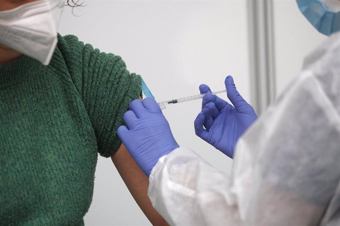 Archivo - Un empleada sanitaria suministra la vacuna contra la Covid-19 en el dispositivo de vacunación puesto en marcha en el polideportivo Germans Escales.