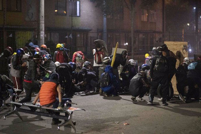 26 May 2021, Colombia, Bogota: People take cover behind shields during clashes with riot police at a protest against the government of Colombian President Ivan Duque Marquez. Photo: Daniel Garzon Herazo/ZUMA Wire/dpa