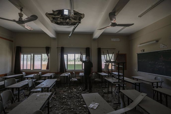 30 May 2021, Palestinian Territories, Gaza City: An employee of the Palestinian Ministry of Education inspects a hole in the ceiling of a damaged classroom at a school that was hit during the recent Israeli airstrikes on the Zeitoun neighbourhood in Gaz